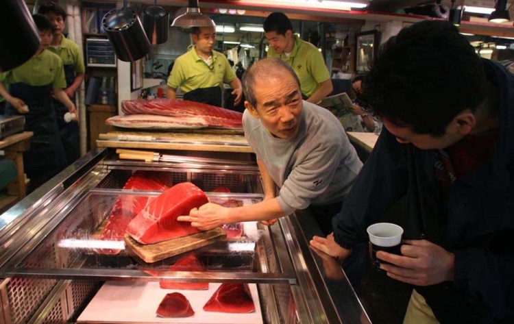 A prospective buyer examines a cut of tuna